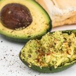Avocado su un tagliere con ingredienti naturali per abbassare il colesterolo, in un contesto di cucina casalinga.